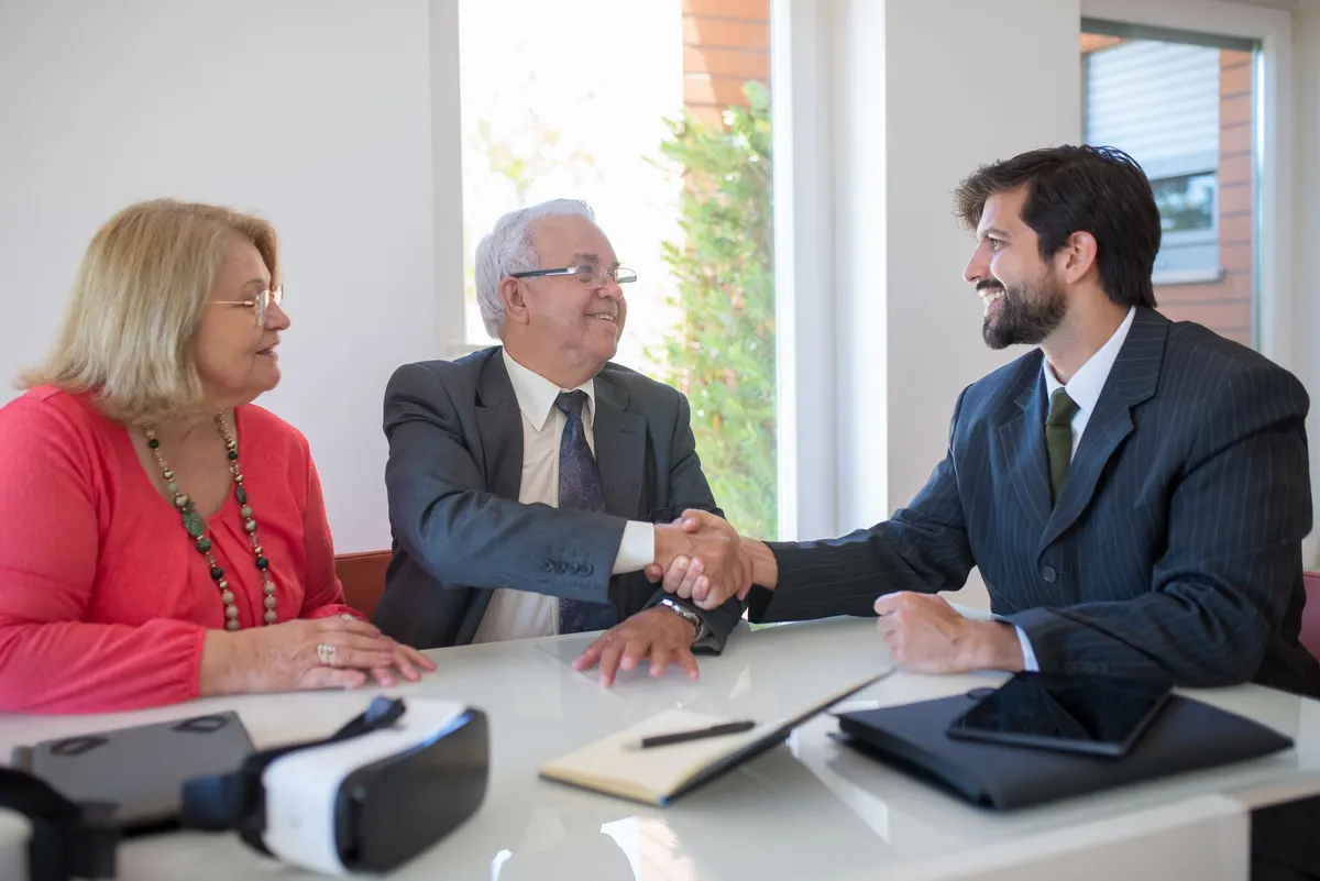 A staffer shakes hands with an older donor across a meeting table