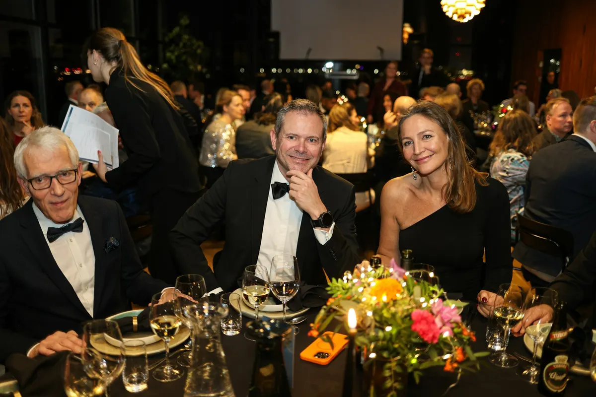 Guests in black tie smiling at a candlelit table during a fundraising dinner