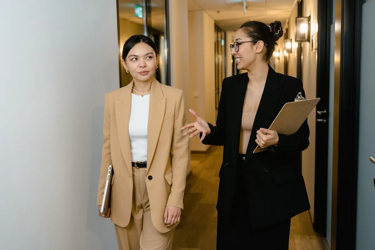 Two colleagues with a clipboard talking in a hallway