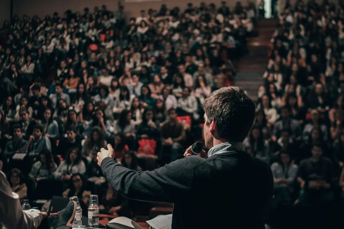 A speaker with a microphone facing a full auditorium