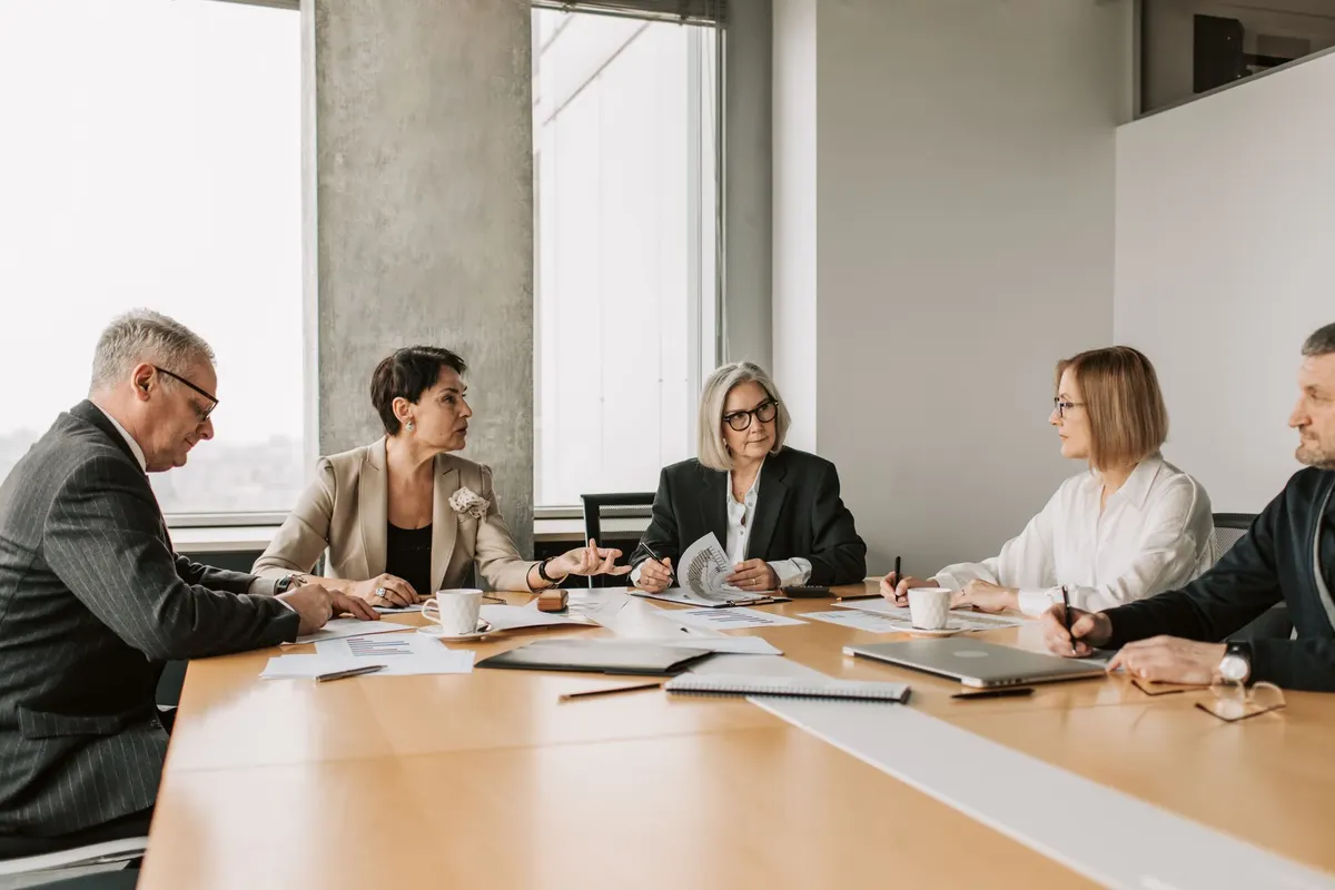 Five colleagues reviewing reports around a conference table in a bright office